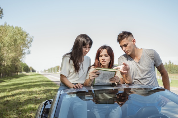 Dua orang wanita dan satu orang pria sedang merencanakan rute menggunakan map